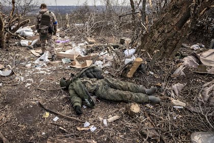 Un soldado ucraniano pasa junto al cuerpo de un soldado ruso tendido en el suelo después de que las tropas ucranianas recuperaran la aldea de Mala Rogan, al este de Kharkiv, el 30 de marzo