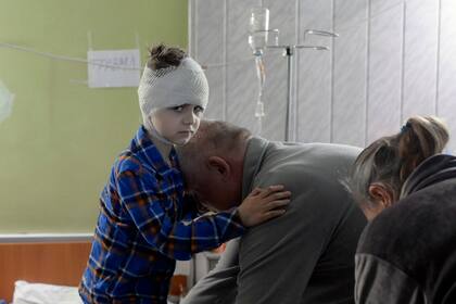 Misha, de 5 años, que perdió a su madre hace unas semanas y resultó herida durante un ataque ruso, recibe ayuda de su abuelo para vestirse en el sótano de un hospital el 26 de marzo