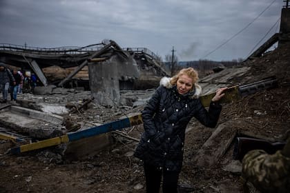 Una mujer descansa después de cruzar un puente destruido mientras evacua de la ciudad de Irpin, al noroeste de Kyiv. La propuesta rusa de un paso seguro desde Kharkiv, Kyiv, Mariupol y Sumy se produjo después de que civiles ucranianos aterrorizados fueran atacados en intentos previos de alto el fuego.