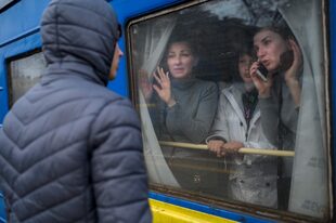 Una familia en un tren de evacuación saluda a un joven que se queda en la plataforma en la estación central de Odessa 