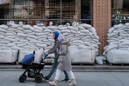 Una pareja camina frente a una tienda cubierta por sacos de arena en Dnipro, Ucrania, el 20 de abril ,en medio de la invasión militar rusa lanzada contra Ucrania