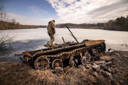 Un militar ucraniano camina sobre los restos de un tanque ruso que fue destruido en la ciudad de Trostyanets, cerca de la frontera con Rusia