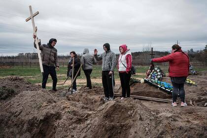 Los familiares de Mykhailo Romaniuk, de 58 años, asesinado a tiros en su bicicleta el 6 de marzo, esperan para enterrar su ataúd en un cementerio de Bucha,