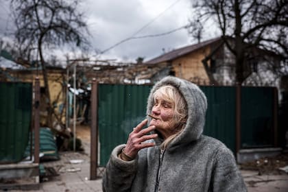 Vera Tsyghanova, de 76 años, fuma un cigarrillo frente a lo que quedó de su casa, que resultó dañada en un bombardeo aéreo en la ciudad de Irpin