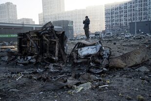 Un hombre se encuentra encima de un coche destruido en medio de la destrucción causada tras el bombardeo de un centro comercial, en Kiev, Ucrania, el lunes 21 de marzo de 2022.