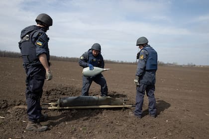 Técnicos de desactivación de bombas retiran un cohete sin detonar cargado con municiones en racimo de un campo en el pueblo de Ridnyi Krai, Ucrania