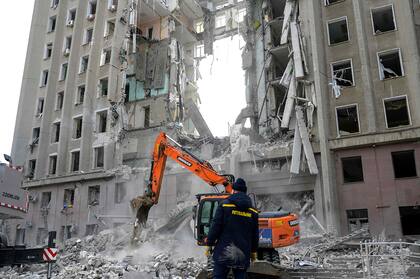 TOPSHOT - A worker watches an excavator clearing the rubble of a government building hit by Russian rockets in Mykolaiv on March 29, 2022. - A Russian strike battered the regional government building in the southern Ukrainian city of Mykolaiv, a key port under heavy assault for weeks, the regional governor said on March 29, 2022. Governor Vitaly Kim said that most people inside the building had not been injured but several civilians and soldiers were unaccounted for. (Photo by BULENT KILIC / AFP)