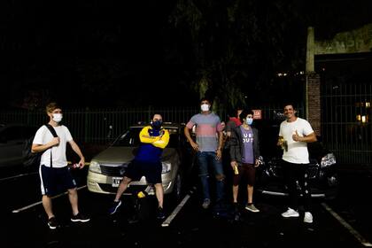 Guido Madeo y sus 10 amigos del barrio toman unas cervezas en el estacionamiento al aire libre de las canchas luego de jugar un partido de futbol