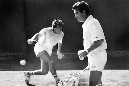 Guillermo Pérez Roldán pega un revés, bajo la mirada de Raúl, durante una pretemporada en Tandil en los 80