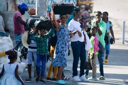 Personas que viven cerca de la Penitenciaría Nacional llevan sus pertenencias mientras abandonan la zona en Puerto Príncipe, Haití, el 4 de marzo de 2024.