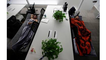 Han Liqun (a la izquierda) de Renren crédito Management Co.,duerme junto al ingeniero Xiang Siyang en camas de campaña en la oficina después de terminar el trabajo temprano en la mañana