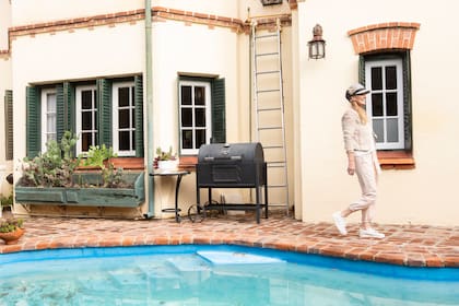Hay un jardín lleno de plantas y una pileta con mesas para estar al aire libre