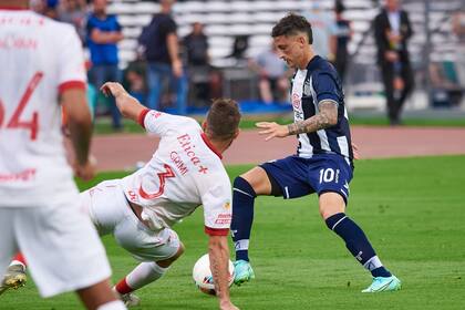 Héctor Fértoli, uno de los jugadores más habilidosos de Talleres, trata de superar a Grimi