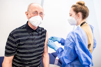 Heinrich Atoni recibe una dosis de la vacuna de Pfizer-BioNTech en el centro de vacunación instalado en el recinto ferial de Bremen, noroeste de Alemania