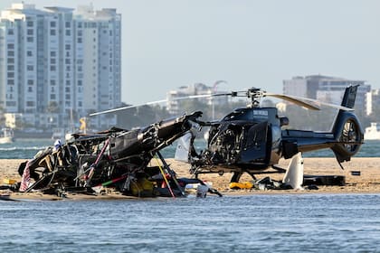 Two cashed helicopters sit on the sand at a collision scene near Seaworld, on the Gold Coast, Australia, Monday, Jan. 2, 2023. The 2 helicopters collided killing several passengers and critically injuring a few others in a crash that drew emergency aid from beachgoers enjoying the water during the southern summer. (Dave Hunt/AAP Image via AP)