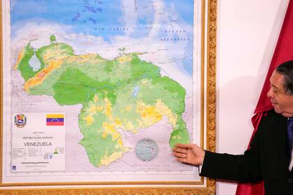 Hermann Escarra, presidente de una comisión venezolana sobre la disputa territorial con Guyana, junto a un mapa en que el Esequibo está integrado al territorio venezolano
