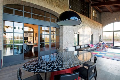 El living comedor, superluminoso gracias a los enormes ventanales que dan al jardín, está presidido por una gran mesa ovalada de resina con diseño de inspiración pop.