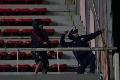 Hinchas de Universidad de Chile lanzan piedras durante el partido de vuelta de la serie de octavos de final de Copa Sudamericana en la cancha de Independiente.