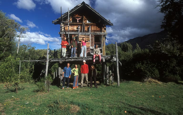 Grupo de Arte x Conservación reunidos en la chacra de Alejandra Piovano y Balín Sívori en Epuyén (2001). Esta casa palafito fue construida por Pato Pertile y Marco Sauter, primeros hippies en llegar a Epuyén. (Foto: Lucas Chiappe)