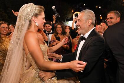 El diseñador ajusta el impresionante vestido que su nuera lució en la fiesta de boda: una cola de tres metros y medio de largo, con un velo bordado con mil lentejuelas color oro