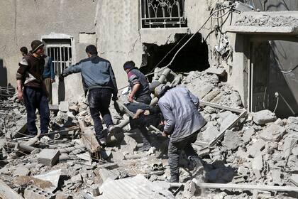 Hombres ayudan a gente herida tras los bombardeos en el barrio de Hamouriyeh, en Ghouta Oriental