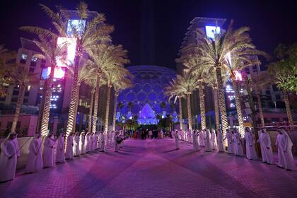 Hombres emiratíes hacen fila para recibir a los visitantes en el sitio de la Expo 2020, el día de su apertura en el Emirato del Golfo de Dubai.