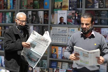 Hombres jordanos leen periódicos locales con titulares sobre los últimos eventos en su país, frente a un quiosco en la capital, Ammán, el 4 de abril de 2021