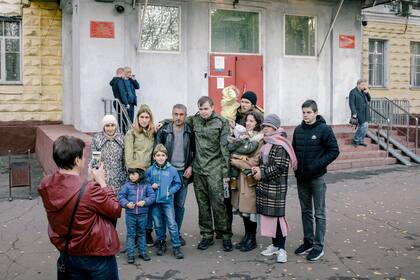 Hombres que han sido reclutados posan para una fotografía con familiares en una oficina de reclutamiento en Moscú el martes 11 de octubre de 2022
