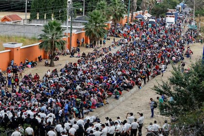 Hondureños que participan en una nueva caravana de migrantes, que se dirigirá a Estados Unidos, se reúnen frente a policías que bloquean la carretera en Vado Hondo, Guatemala