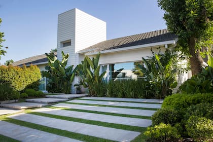 Hormigón y pasto se alternan en la entrada para autos, mientras que con formas más cuadrada bajan los peldaños que siguen la sutil pendiente del terreno.