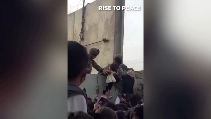 Una niña afgana es levantada entre la multitud para ser rescatada por soldados estadounidenses