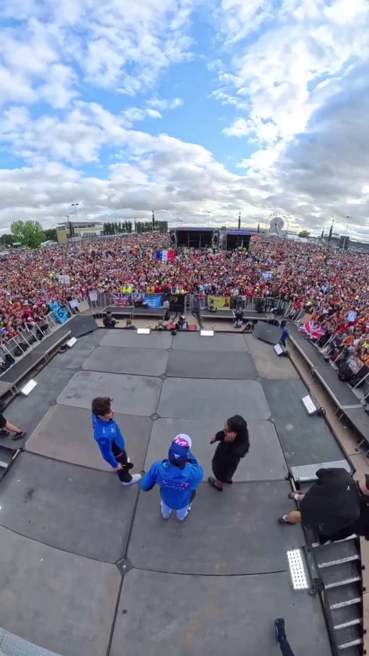 Franco Colapinto y su compañero Pierre Gasly saludan a una multitud desde el escenario de la fan zone tras la clasificación para el domingo