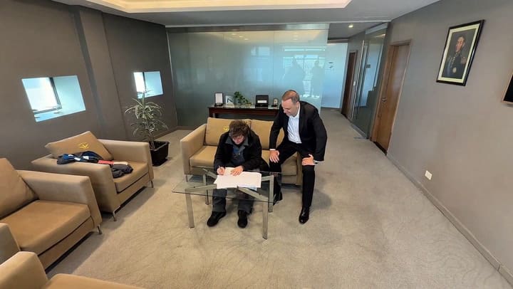 Milei cuando firmó la reforma laboral acompañado por Adorni