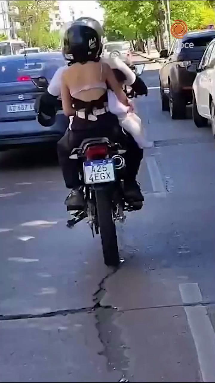 Una pareja viajó en moto con su bebé colgando de un brazo en plena avenida