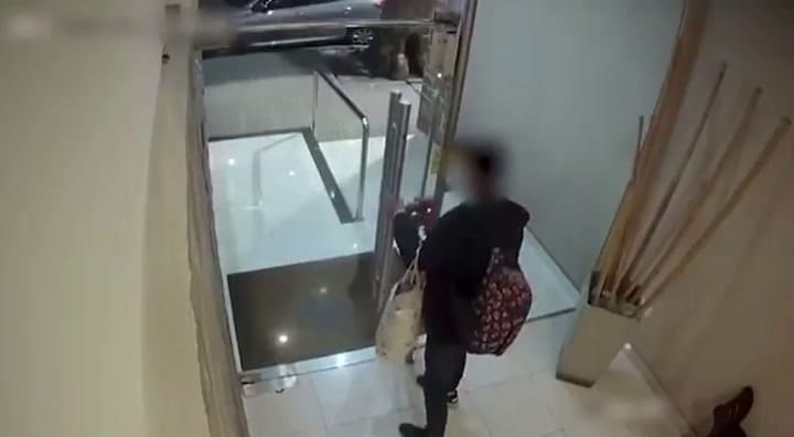 El momento en el que el delicuente entra al edificio y es detenido por la policía