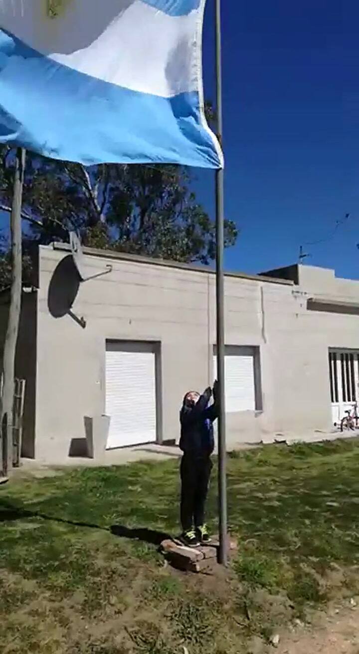 El nene izando la bandera y cantando el himno