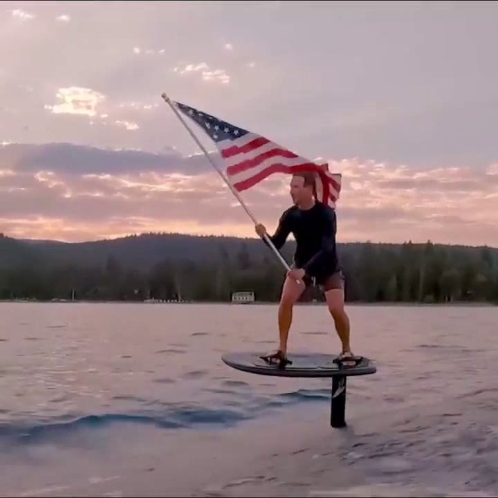 Mark Zuckerberg flamea una bandera estadounidense mientras surfea en su tabla eléctrica