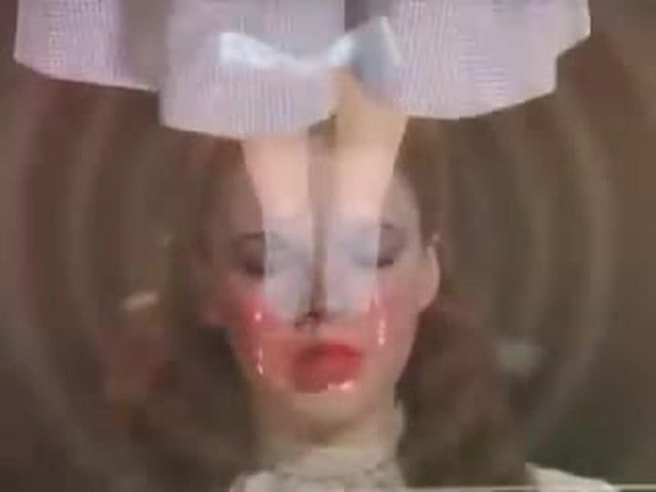 Os pés da boneca Karen Marsh no rosto de Judy Garland em O Mágico de Oz