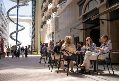 Huéspedes disfrutan de bebidas en el Coffee Emporium en el World Promenade, a bordo del nuevo barco