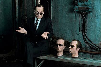 Hugo Weaving, acompañado por dos máscaras del agente Joe Smith que interpretó en la saga de Matrix