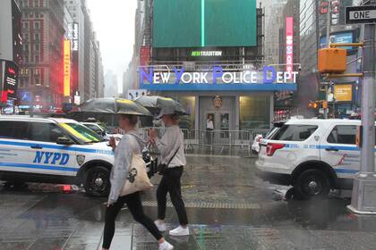 Los peatones se protegen de las fuertes lluvias con paraguas al cruzar una calle en Times Square cuando la tormenta tropical Henri toca tierra en Nueva York