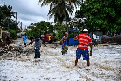La gente camina entre las inundaciones causadas por el agua de mar después del paso del huracán Beryl en la parroquia de Saint James, Barbados, cerca de Bridgetown, Barbados, el 1 de julio de 2024