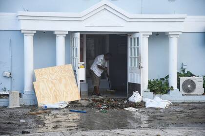 Un hombre limpia la basura de un restaurant que resultó dañado tras el paso del huracán