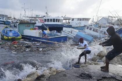 Pescadores tiran de un barco dañado por el huracán Beryl de regreso al muelle en Bridgetown Fisheries en Barbados, el lunes 1° de julio de 2024