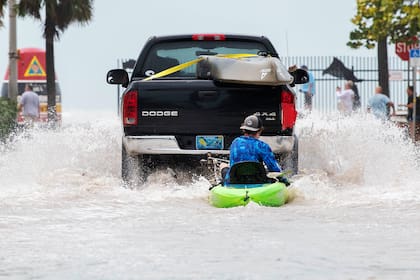 Una camioneta arrastra a un hombre en un kayak en un camino después de la inundación tras el paso del huracán Ian, en Key West