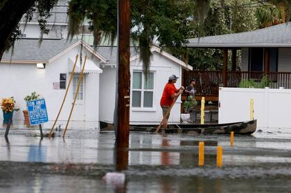 Una mujer sale de su casa con un bote mientras el huracán avanza y el agua no deja de subir