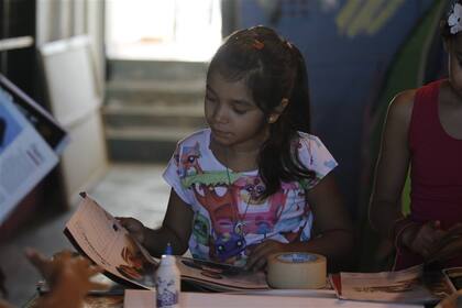 Iara, de 9 años, hojea unas revistas en el taller de reciclado del Centro Cultural Puertas Al Arte, en Beccar, provincia de Buenos Aires