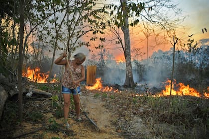 Idelia Lima Lisboa, esposa de un agricultor que prendió fuego a la selva tropical alrededor de su propiedad, intenta despejar un camino de hojas secas cuando el fuego se acerca a su casa en un área de la selva amazónica, al sur de Novo Progresso en el estado de Pará, Brasil, en agosto 15, 2020