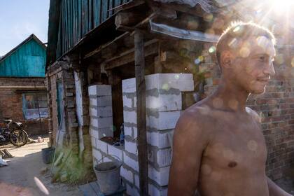 Ihor Bykov, profesor de secundaria, reconstruye una pared de su casa después de que fuera dañada por un ataque ruso en Nikopo