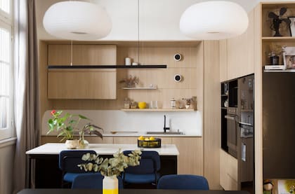 Iluminación lineal sobre isla y apliques de pared en la alzada de la cocina (Huup). Colgantes sobre la mesa del comedor (Iluminación Agüero). Alacenas y bajomesadas en melamina ‘Kaiserberg’ (Egger) y MDF laqueado en negro.